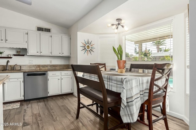 kitchen featuring a sink, visible vents, stainless steel dishwasher, and light wood-style flooring