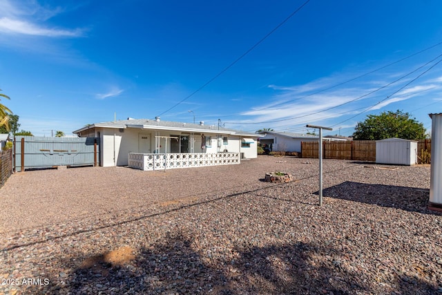 back of house with a storage unit