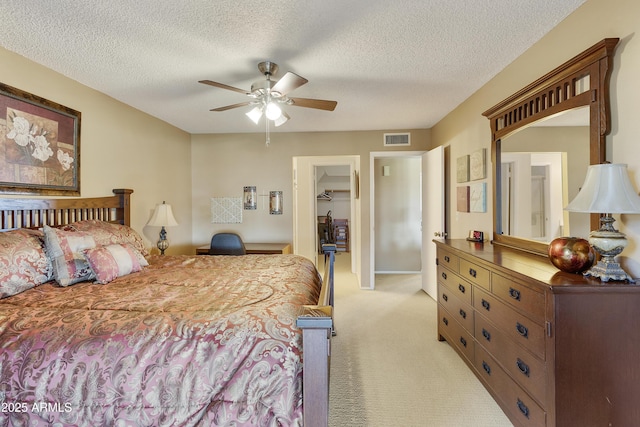 carpeted bedroom featuring ceiling fan, a spacious closet, a closet, and a textured ceiling