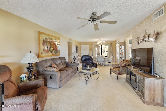 carpeted living room with ceiling fan and a textured ceiling