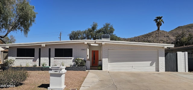 mid-century modern home featuring brick siding, driveway, central AC, and an attached garage