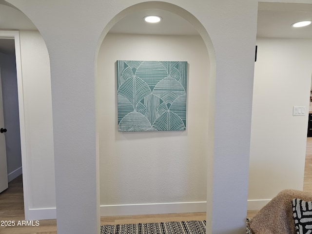 interior details featuring arched walkways, baseboards, and wood finished floors