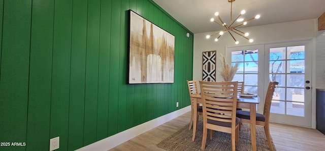 dining room featuring baseboards, a notable chandelier, and light wood-type flooring