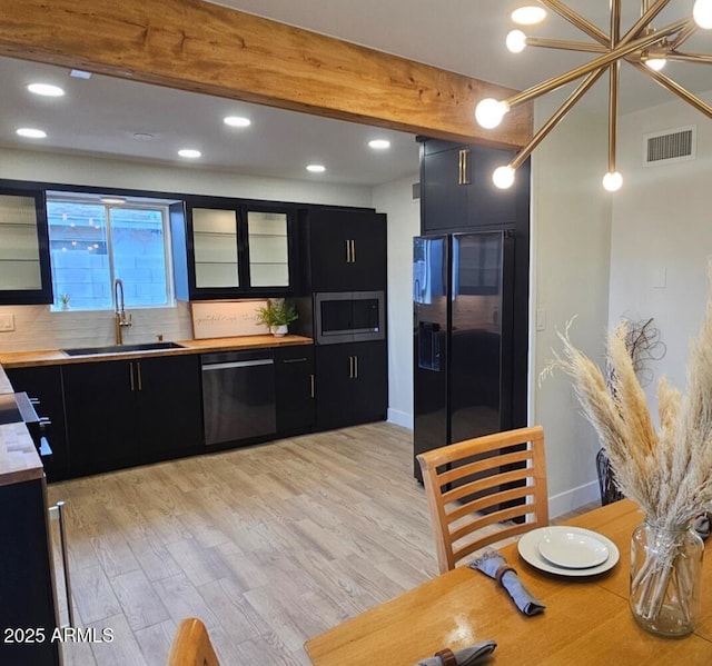 kitchen with visible vents, a sink, dishwashing machine, and dark cabinets