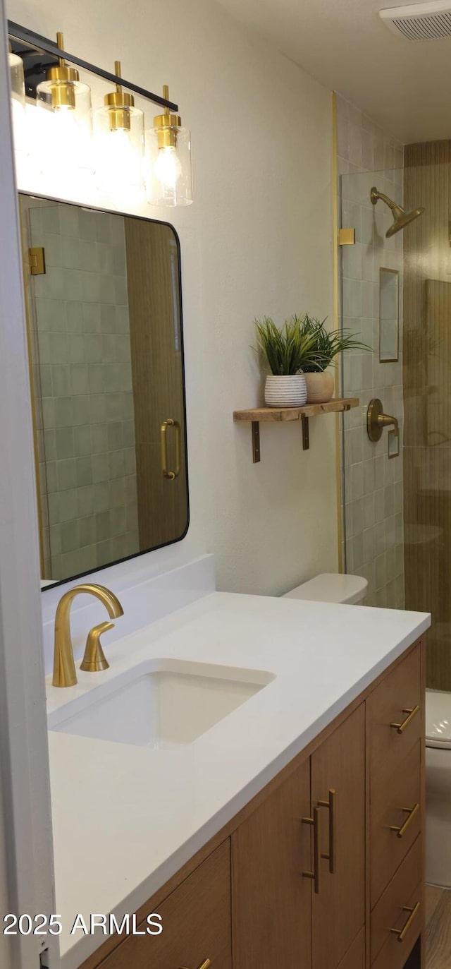 full bathroom featuring a stall shower, visible vents, toilet, and vanity