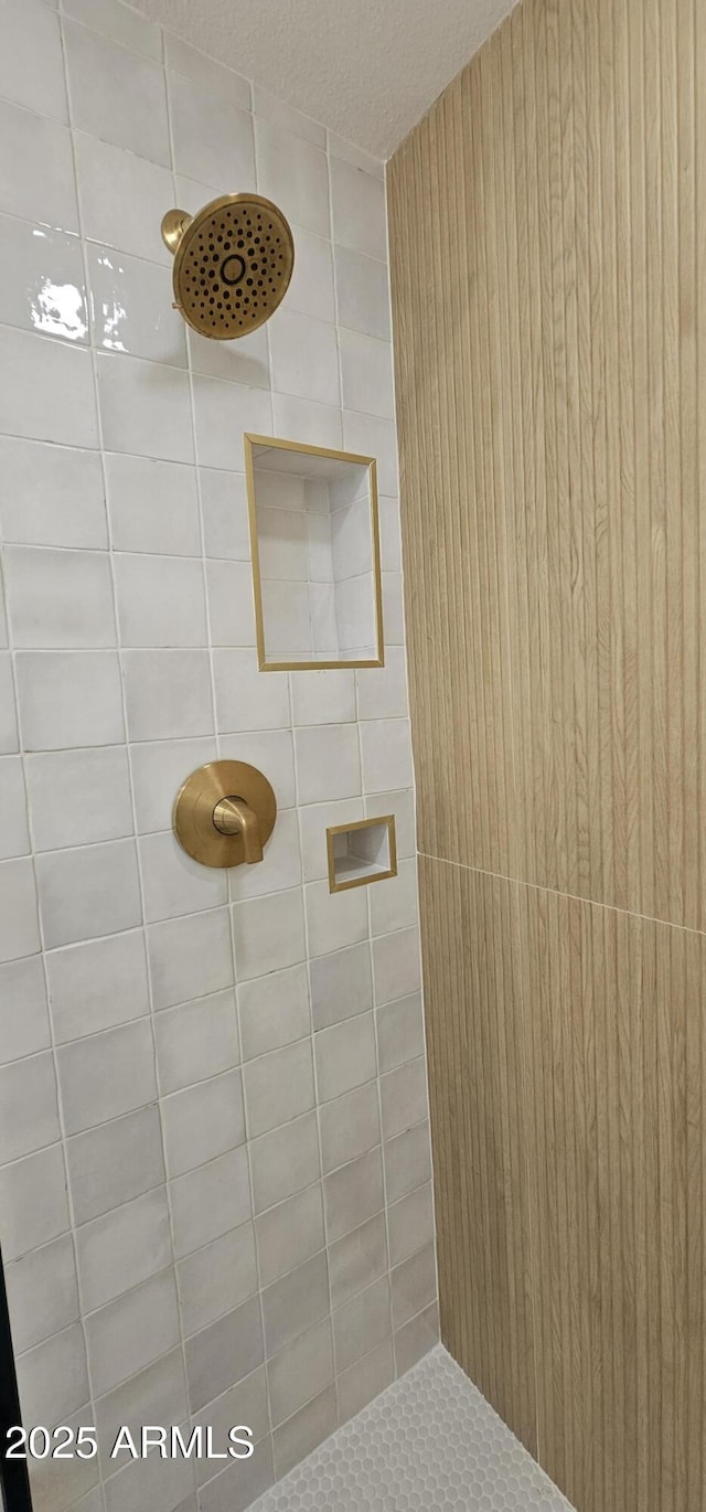 full bathroom featuring tiled shower and a textured ceiling