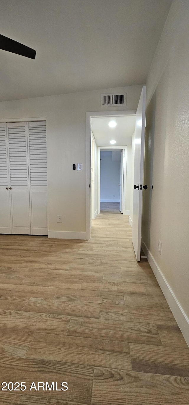 corridor with baseboards, visible vents, and light wood-type flooring