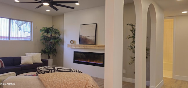 living area featuring ceiling fan, wood finished floors, a glass covered fireplace, and recessed lighting