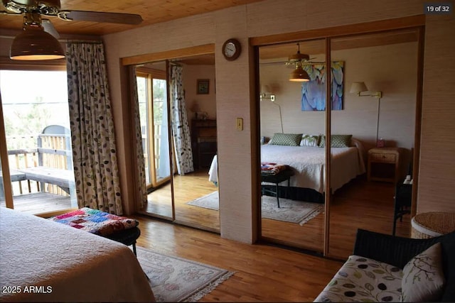 bedroom with wood-type flooring, access to outside, and two closets