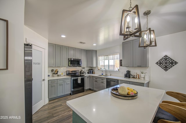 kitchen featuring visible vents, stainless steel appliances, a sink, gray cabinetry, and backsplash