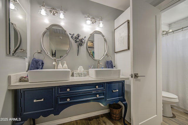 full bathroom with wood finished floors, toilet, and vanity