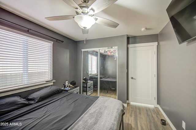 bedroom featuring light wood-style flooring, baseboards, a closet, and ceiling fan