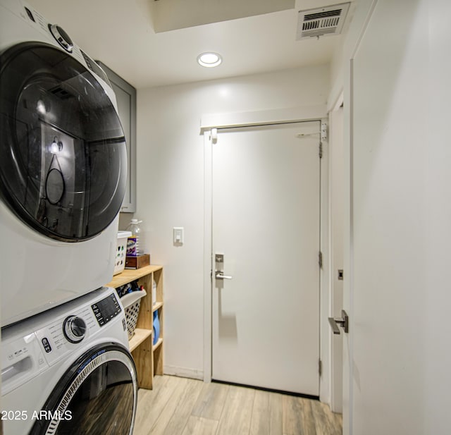 laundry room with light wood-type flooring, stacked washer and clothes dryer, laundry area, visible vents, and recessed lighting