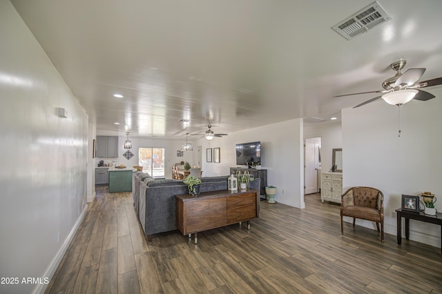 living area with dark wood-style floors, visible vents, baseboards, and a ceiling fan