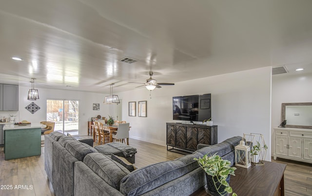living area with visible vents, wood finished floors, and a ceiling fan