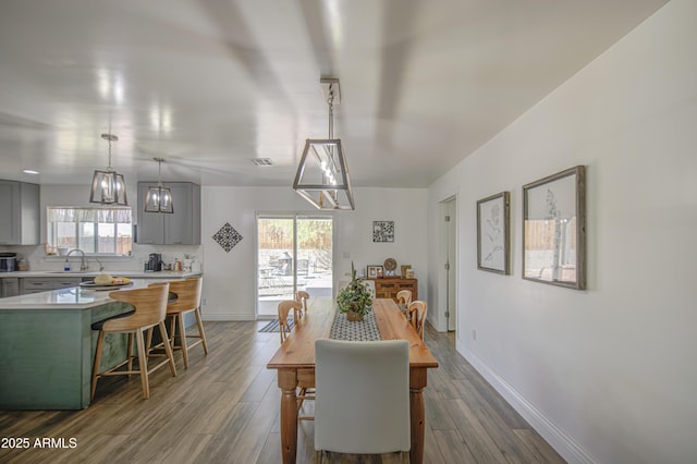 dining space featuring dark wood finished floors, baseboards, visible vents, and a notable chandelier