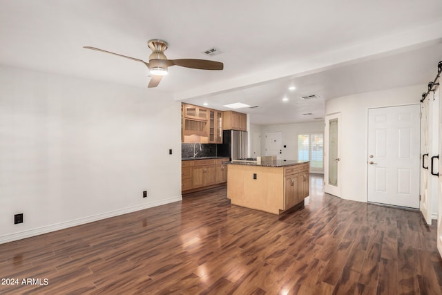 kitchen featuring stainless steel fridge, tasteful backsplash, a center island, ceiling fan, and dark hardwood / wood-style floors