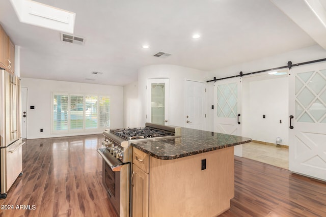 kitchen with a center island, a barn door, dark hardwood / wood-style flooring, light brown cabinetry, and high quality appliances