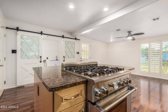 kitchen with ceiling fan, a barn door, dark hardwood / wood-style flooring, and high end range