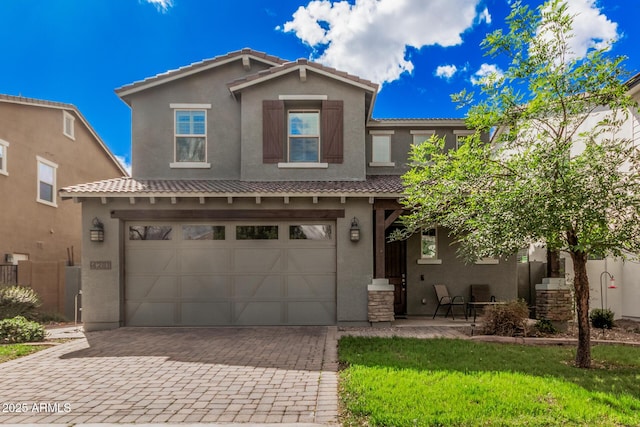 view of front of house featuring a garage, a tiled roof, decorative driveway, and stucco siding