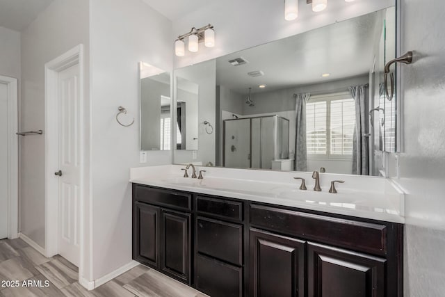 full bathroom with a sink, double vanity, a shower stall, and visible vents