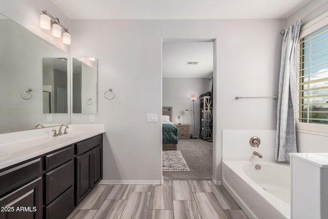 ensuite bathroom with baseboards, visible vents, ensuite bath, vanity, and a bath