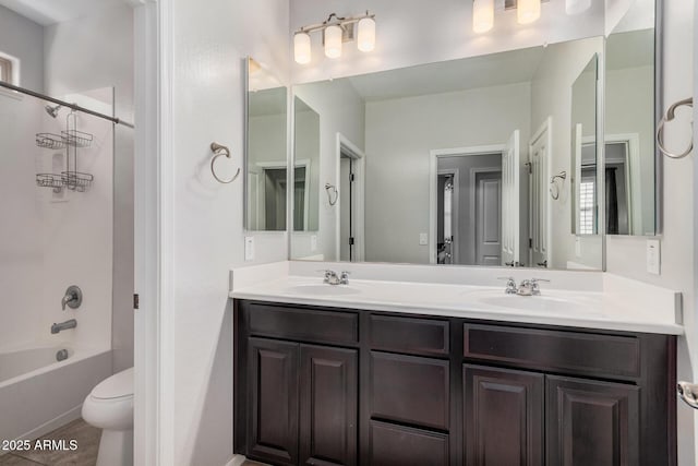 bathroom featuring double vanity, toilet, a sink, and shower / bathtub combination