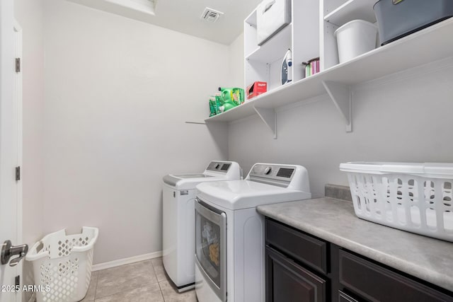 laundry room with light tile patterned flooring, visible vents, baseboards, cabinet space, and washing machine and clothes dryer