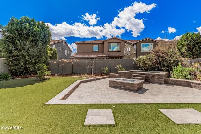 rear view of house with a yard, an outdoor fire pit, a fenced backyard, and a patio