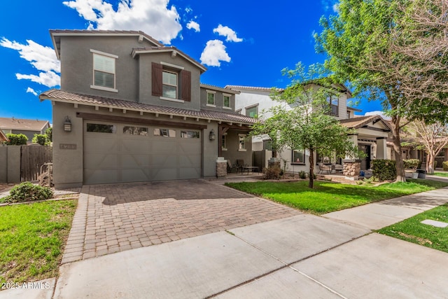 mediterranean / spanish house featuring decorative driveway, stucco siding, an attached garage, a front yard, and fence