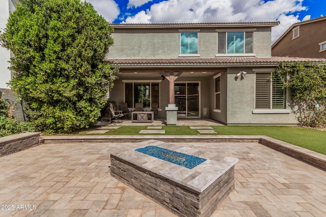 rear view of property with a fire pit, a patio, a tiled roof, and stucco siding