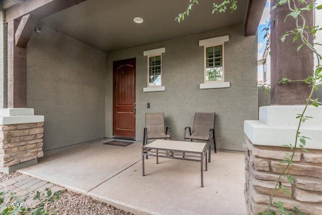 view of exterior entry with a patio and stucco siding