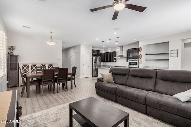 living area with light wood-style flooring, visible vents, a ceiling fan, and recessed lighting