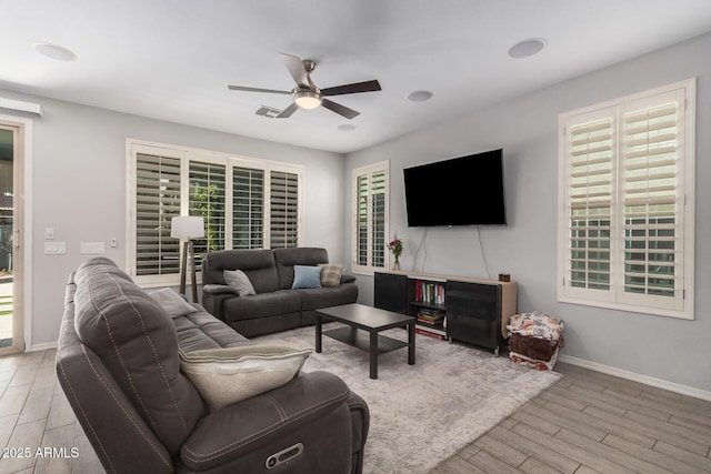 living room featuring a ceiling fan, plenty of natural light, baseboards, and wood finished floors