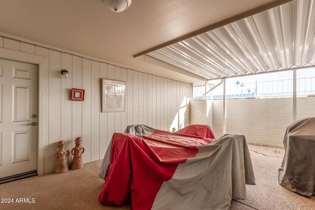 carpeted bedroom featuring wood walls