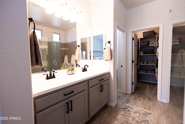 1364 W Spine Tree Ave, Queen Creek, AZ 85140 - bathroom featuring double vanity, a spacious closet, a shower stall, and wood finished floors