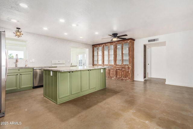 kitchen featuring green cabinetry, a kitchen island, ceiling fan, stainless steel appliances, and light stone countertops