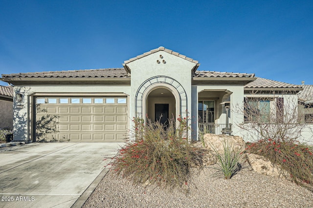 mediterranean / spanish house with an attached garage, a tiled roof, concrete driveway, and stucco siding