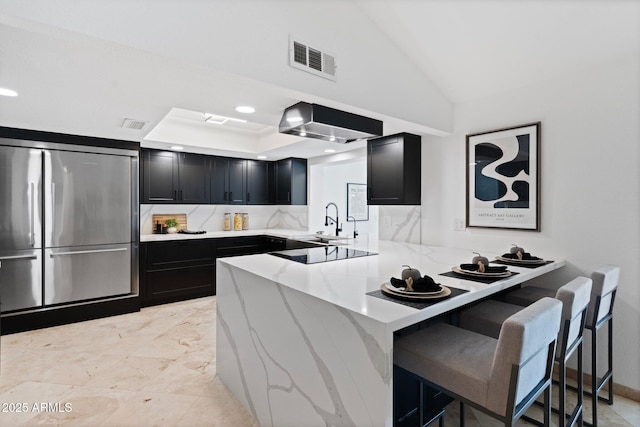 1509 W Kiowa Ave, Mesa, AZ 85202 - kitchen featuring stainless steel fridge, dark cabinets, wall chimney range hood, light stone counters, and a peninsula