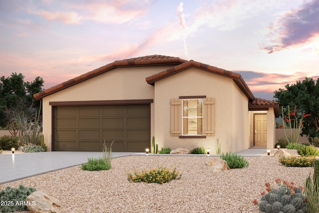 mediterranean / spanish-style home featuring concrete driveway, a tile roof, an attached garage, and stucco siding