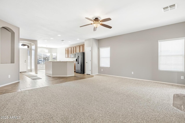 unfurnished living room featuring plenty of natural light, light colored carpet, and ceiling fan