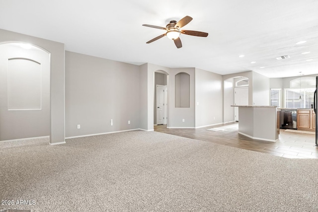 unfurnished living room featuring light carpet and ceiling fan