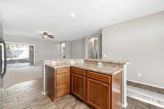 kitchen featuring ceiling fan, a center island, and light stone countertops