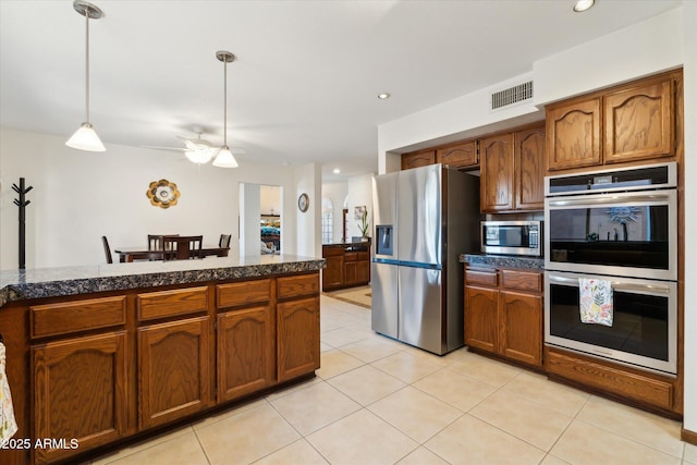 6208 E Paradise Ln, Scottsdale, AZ 85254 - kitchen featuring light tile patterned flooring, visible vents, brown cabinetry, stainless steel appliances, and tile countertops