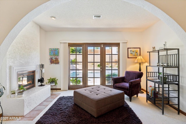 6208 E Paradise Ln, Scottsdale, AZ 85254 - sitting room featuring a glass covered fireplace, arched walkways, visible vents, and a textured ceiling