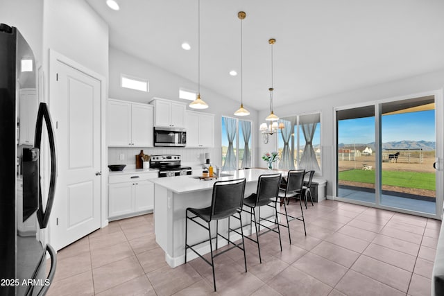 28435 N 249th Ln, Wittmann, AZ 85361 - kitchen with appliances with stainless steel finishes, light tile patterned flooring, a kitchen breakfast bar, a chandelier, and white cabinets
