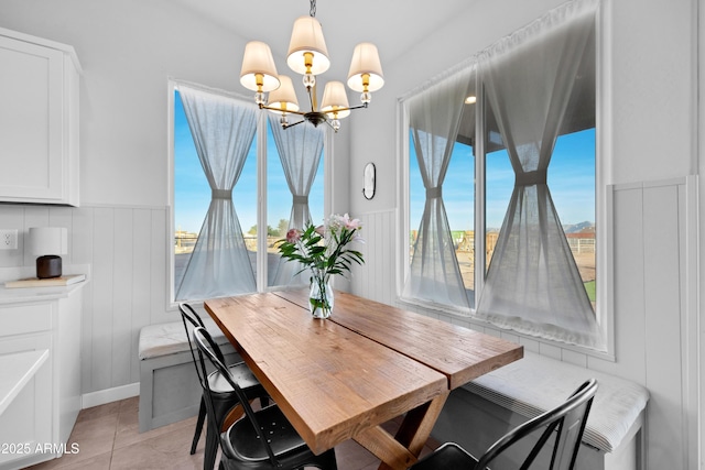 28435 N 249th Ln, Wittmann, AZ 85361 - dining area featuring a chandelier, wainscoting, light tile patterned flooring, and a decorative wall