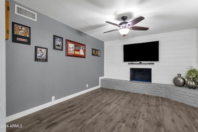 unfurnished living room featuring ceiling fan, a textured ceiling, a fireplace, and wood-type flooring