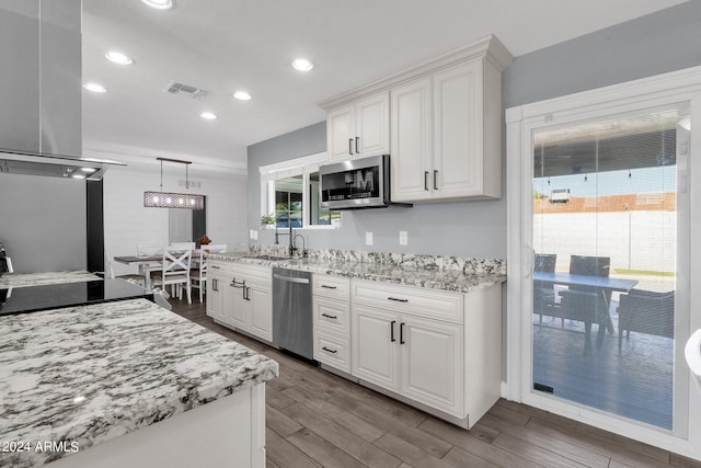 kitchen with pendant lighting, sink, white cabinetry, appliances with stainless steel finishes, and hardwood / wood-style floors