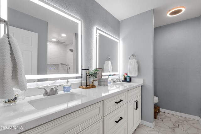 bathroom with a tile shower, vanity, and toilet